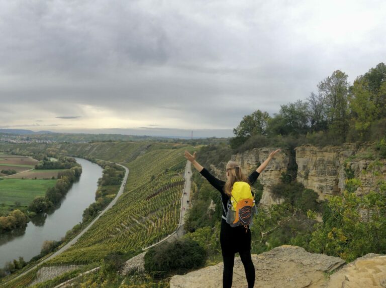 Mareike Walther standing confidently on a rock ledge overlooking vineyards, symbolizing empowerment and freedom in nature