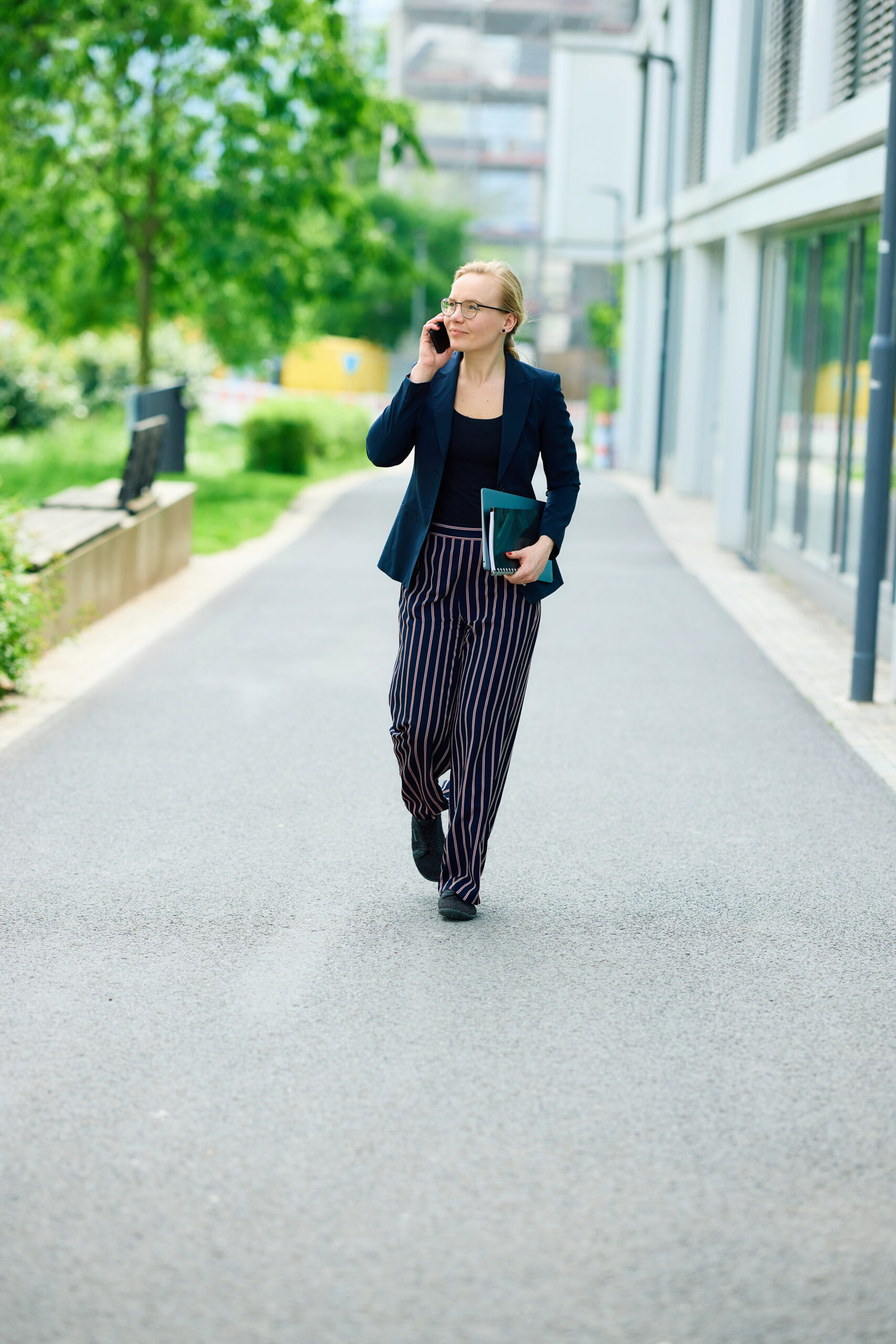 Mareike Walther full-body, walking toward camera while talking on the phone, professional and dynamic